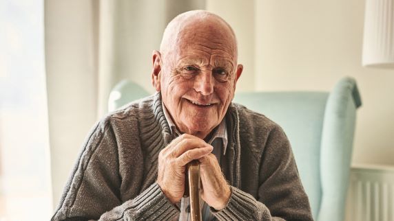 Smiling older man sitting resting on walking stick