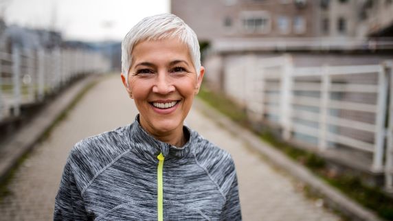 Woman with cropped hair outside smiling at camera