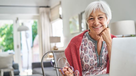 Older woman sitting at a table with a laptop