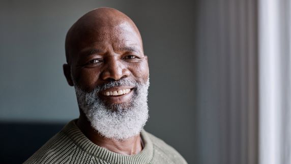 Older man in a room smiling at camera