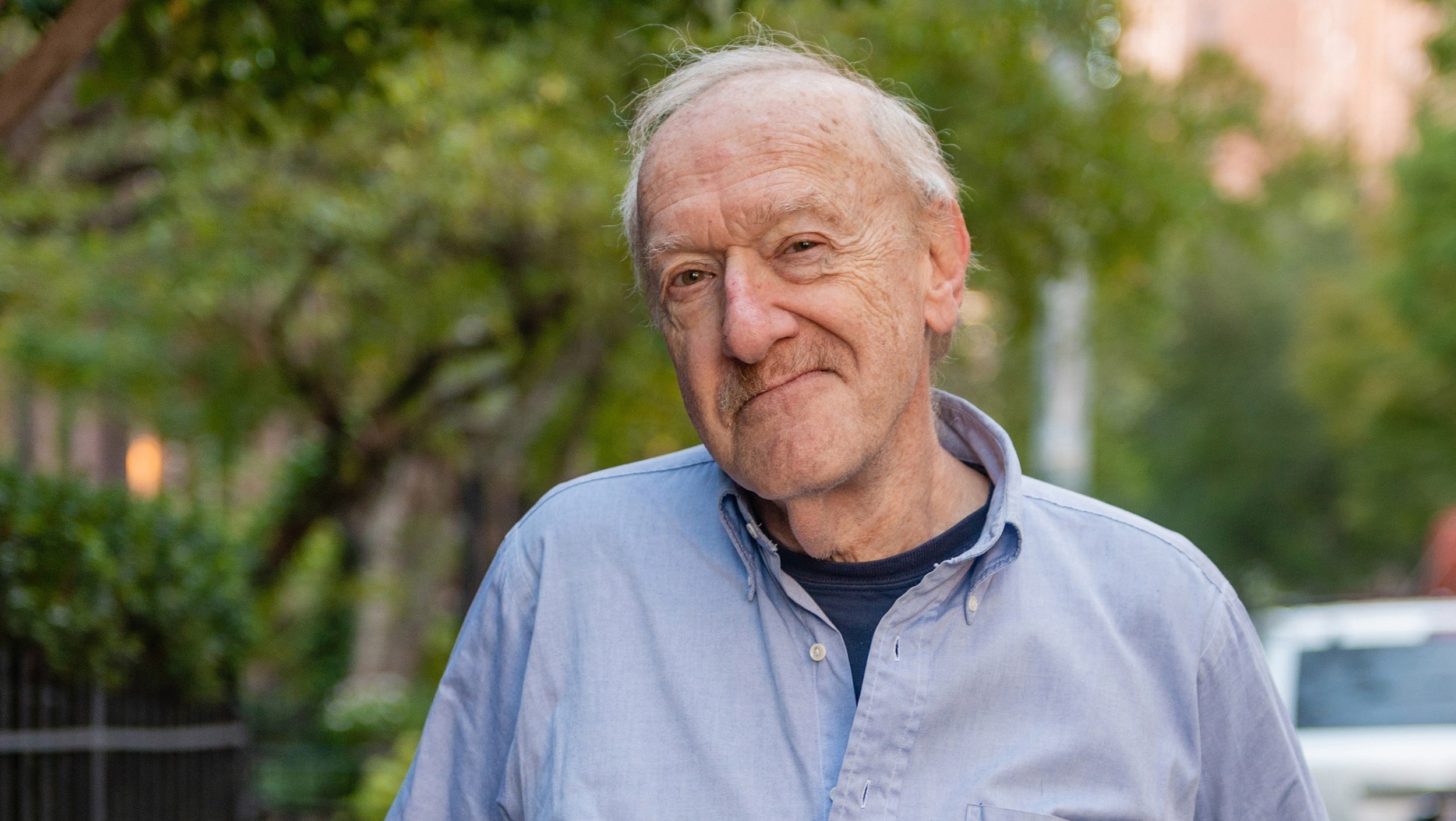 Older man standing in front of trees