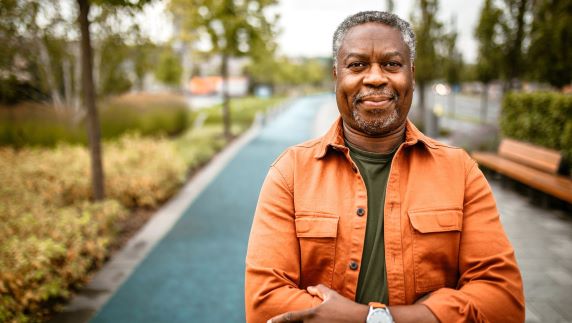 Older man standing in park smiling